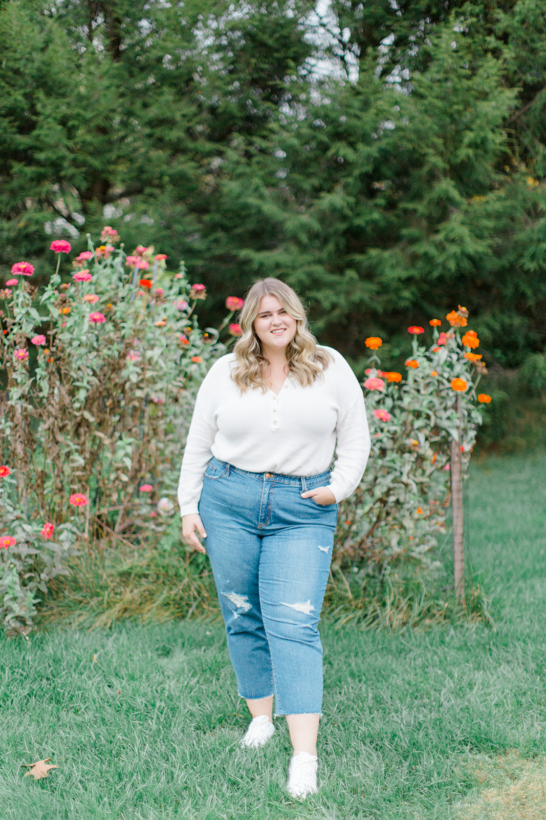 a plus size blonde woman modeling sneaker Shoes With Straight Leg Jeans in a flower garden