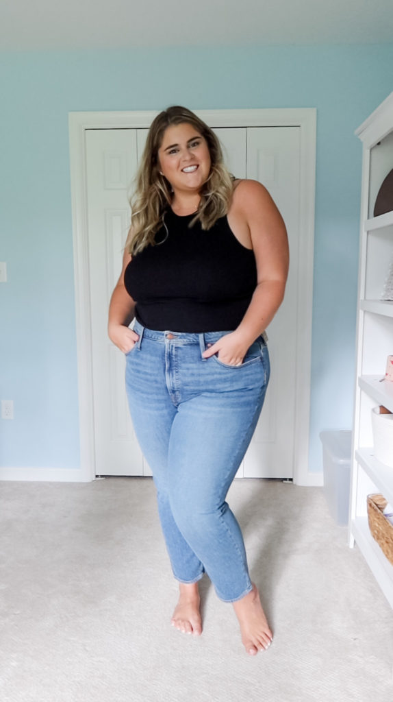 a blonde woman wearing the best plus size skinny jeans and a black tank top