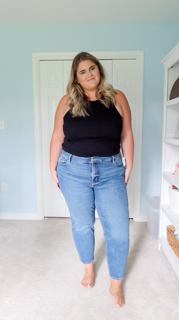 a blonde woman wearing a black tank top and the best plus size mom jeans