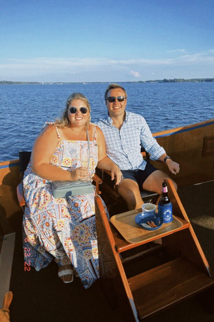 A smiling Caucasian couple posing for a picture on a sailboat in the ocean. 