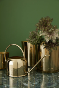 a gold water can on a counter with a planter in a gold planter