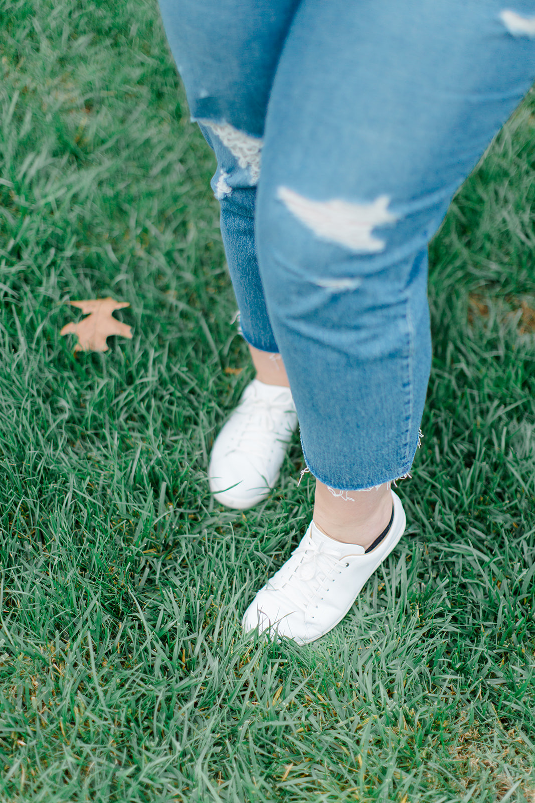 legs wearing tennis Shoes With Straight Leg Jeans in the grass
