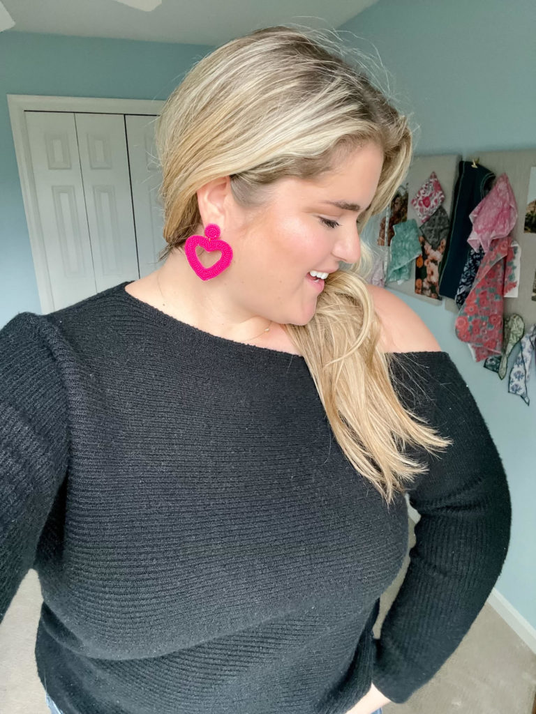 a smiling blonde woman wearing heart earrings as a plus size valentine's day outfit