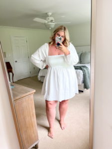 plus size caucasian woman wearing a white wedding shower dress taking a mirror selfie
