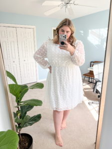 plus size white woman wearing a white bridal shower dress taking a mirror selfie