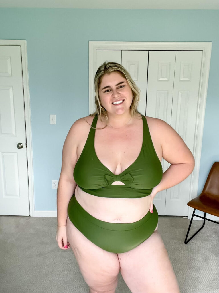 A smiling Caucasian woman is modeling a green Amazon plus size swimwear