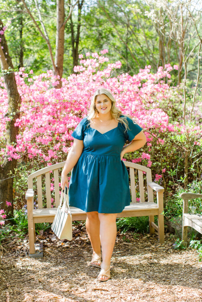 Caucasian woman looking stunning in a teal cotton dress, posing for pictures outdoors.