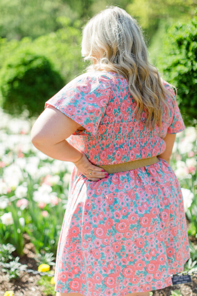 Picture of the smocked back of the Angela dress in Rose Garden worn by a blonde woman outside. 
