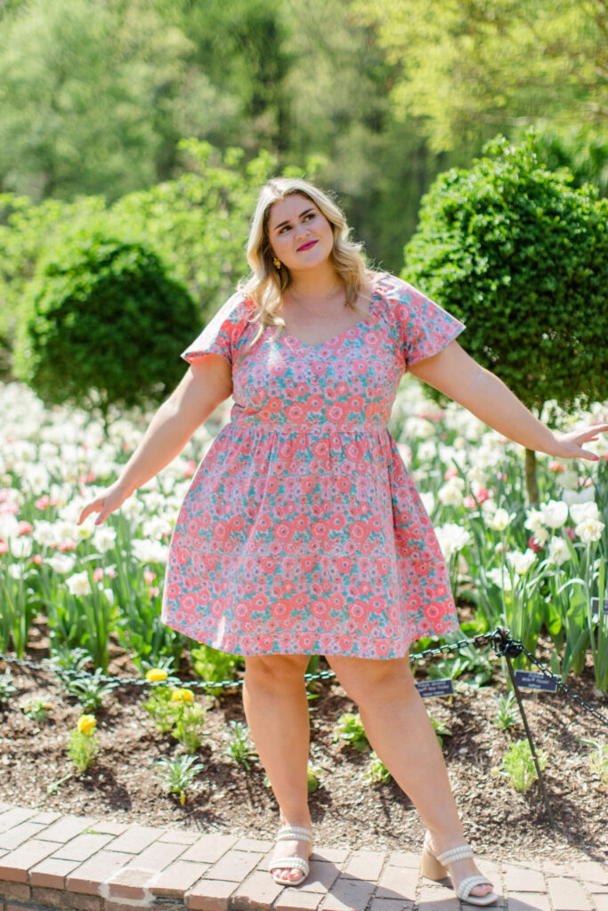 Stunning blonde lady looking gorgeous in a short rose printed cotton dress, taking photos outdoors.