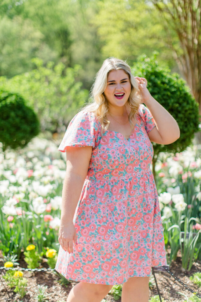 Blonde beauty radiating confidence in a rose printed cotton dress and enjoying an outdoor photo session.